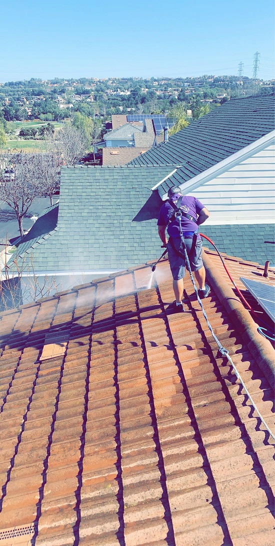 On top of a roof in the OC, cleaning the roof with our pressure washing machine